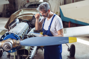Aircraft maintenance mechanic inspects plane engine